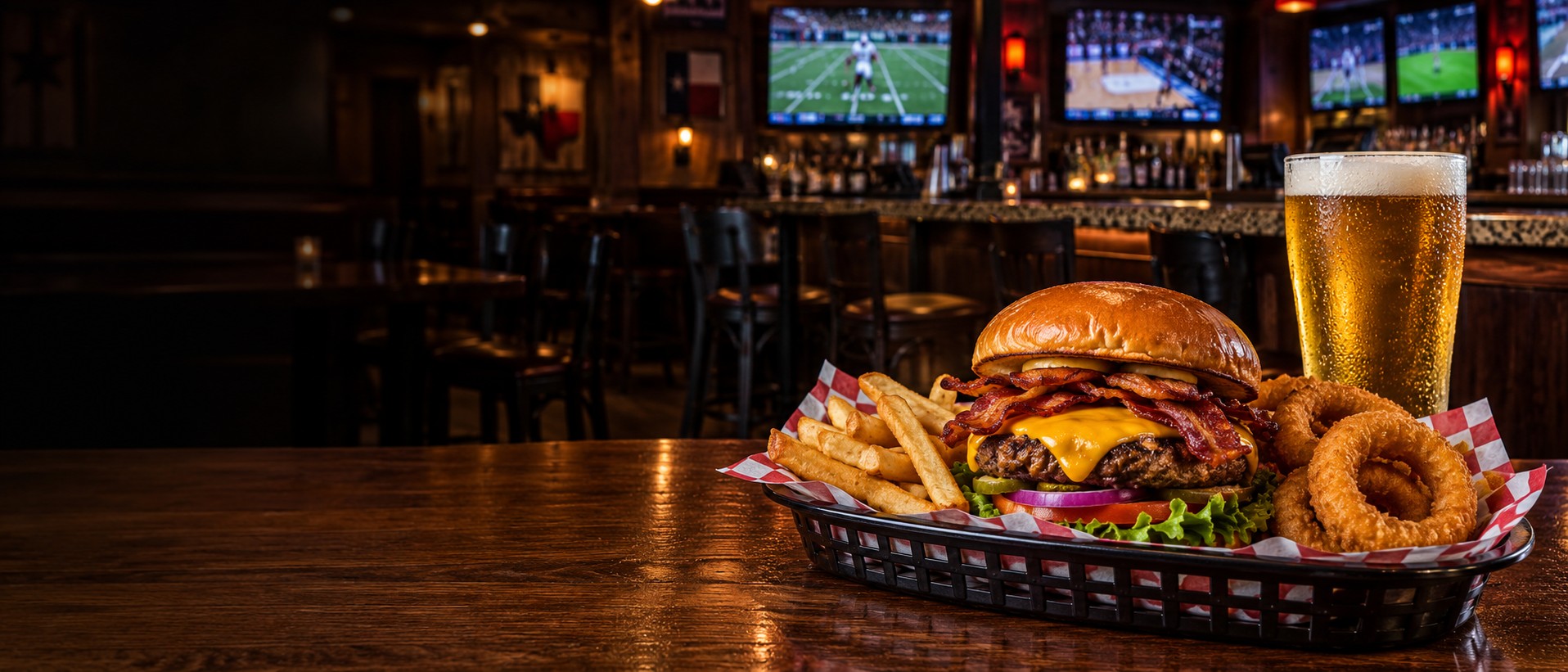 Bacon cheddar burger, fries and a cold beer in a casual sports bar